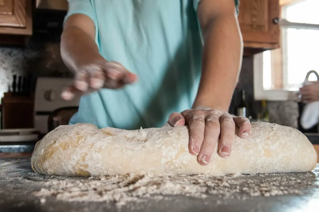 Manos amasando masa de pan sobre la mesada