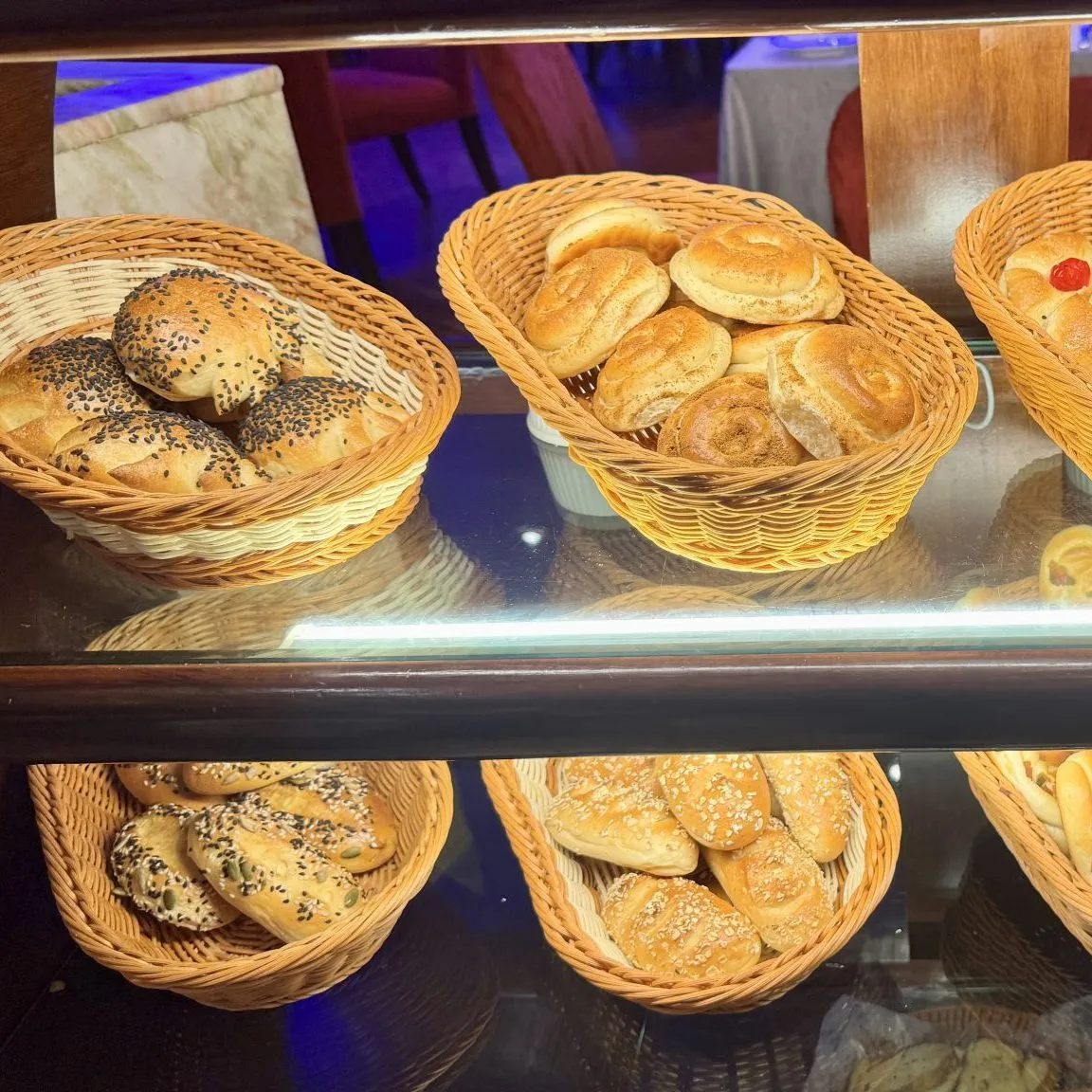 Canastos de mimbre con bollos y panes con semillas en la vidriera