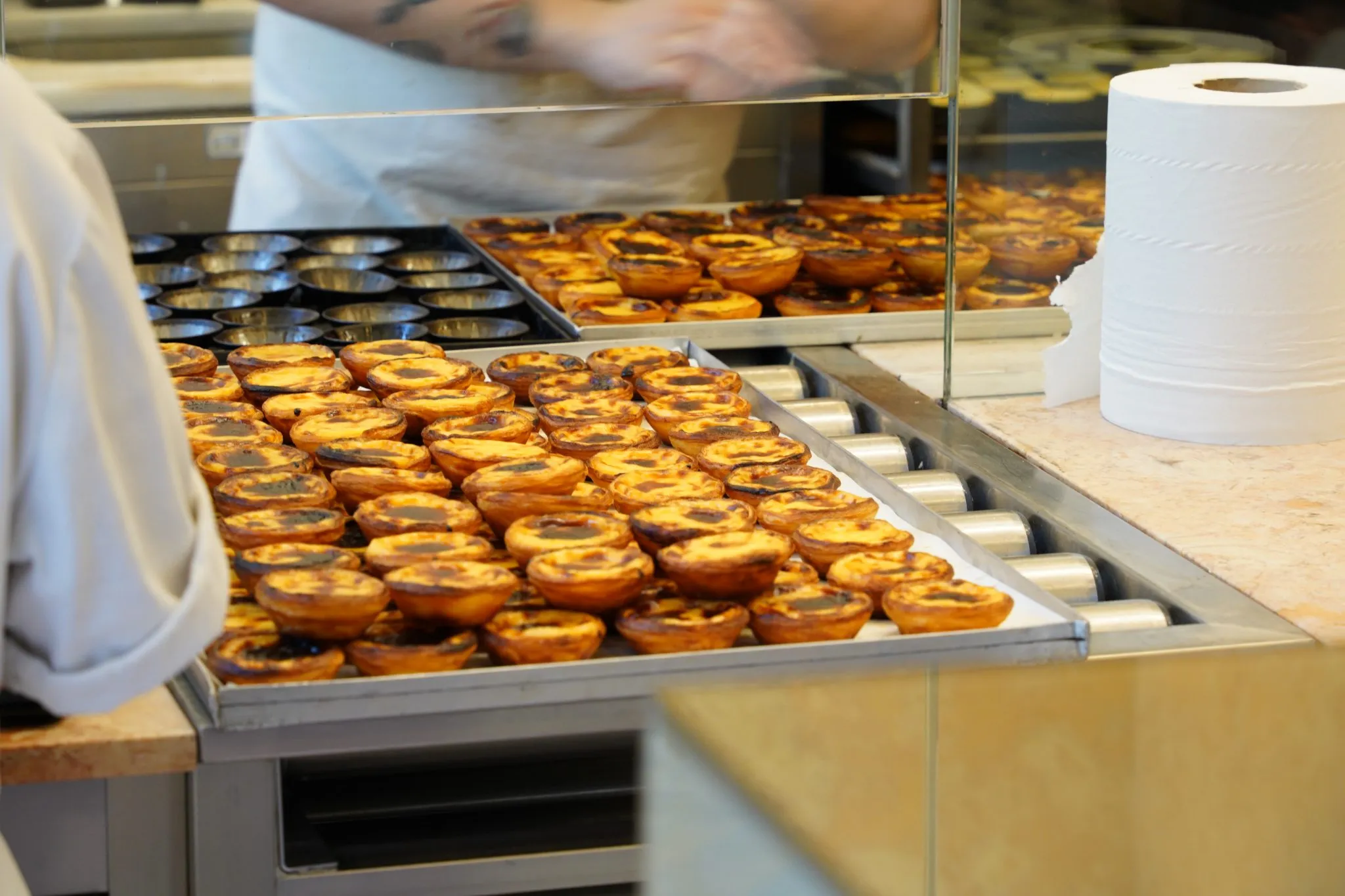Cocina de pastelería con bandejas de tartaletas recién horneadas sobre el mostrador